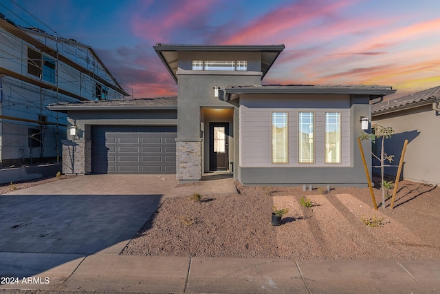 prairie-style house with decorative driveway, an attached garage, and stucco siding