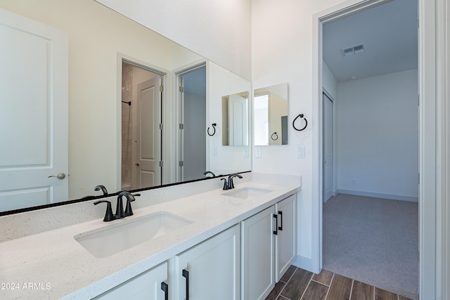 bathroom featuring double vanity, wood finished floors, visible vents, and a sink