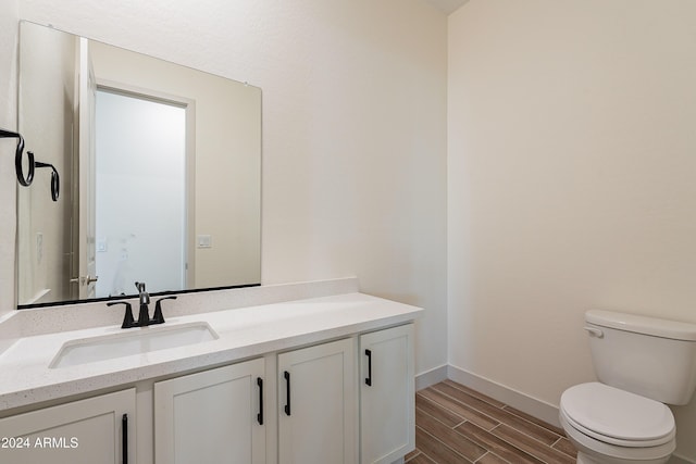 bathroom with vanity, toilet, baseboards, and wood tiled floor