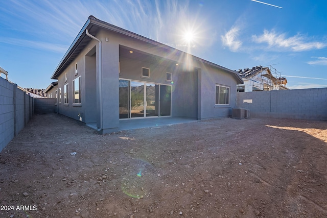 rear view of house with a patio area, central air condition unit, a fenced backyard, and stucco siding