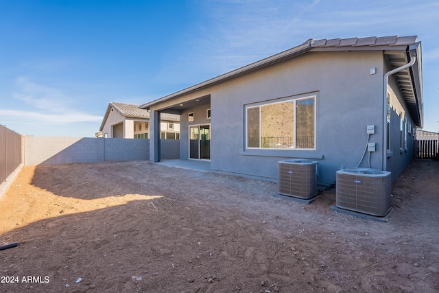 rear view of property featuring a patio area, a fenced backyard, central AC, and stucco siding