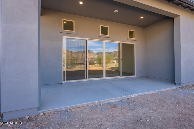 view of exterior entry featuring stucco siding and a patio