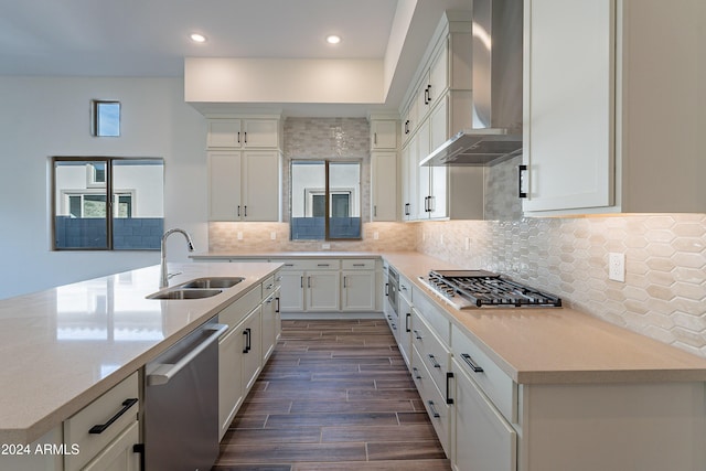 kitchen with a sink, stainless steel appliances, wall chimney exhaust hood, decorative backsplash, and wood tiled floor