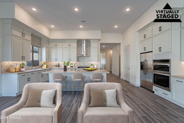 kitchen featuring visible vents, wood finish floors, light countertops, stainless steel appliances, and wall chimney exhaust hood