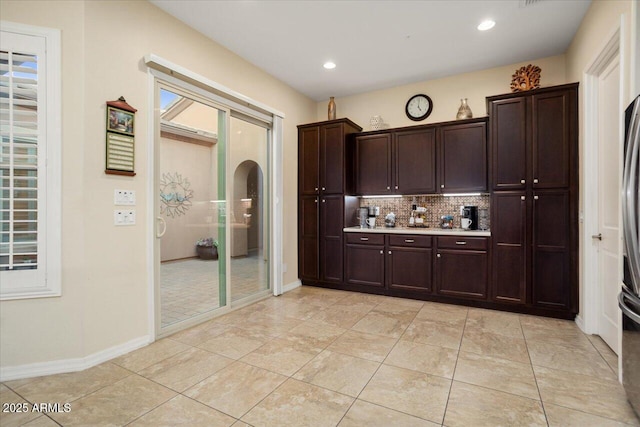 kitchen with backsplash, dark brown cabinetry, a healthy amount of sunlight, and light tile patterned flooring