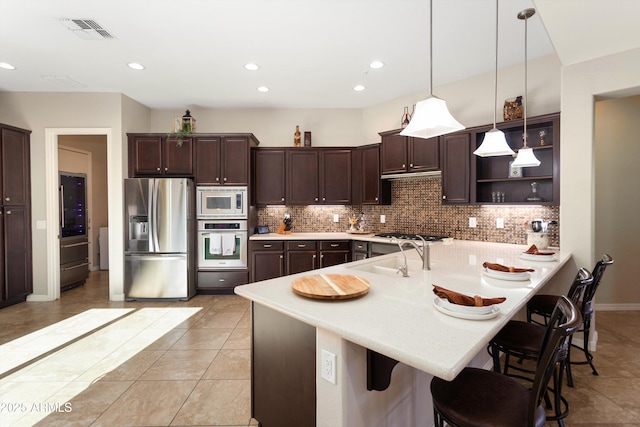 12935 W Lone Tree Trl, Peoria, AZ 85383 - kitchen featuring a sink, dark brown cabinetry, a breakfast bar area, visible vents, and appliances with stainless steel finishes