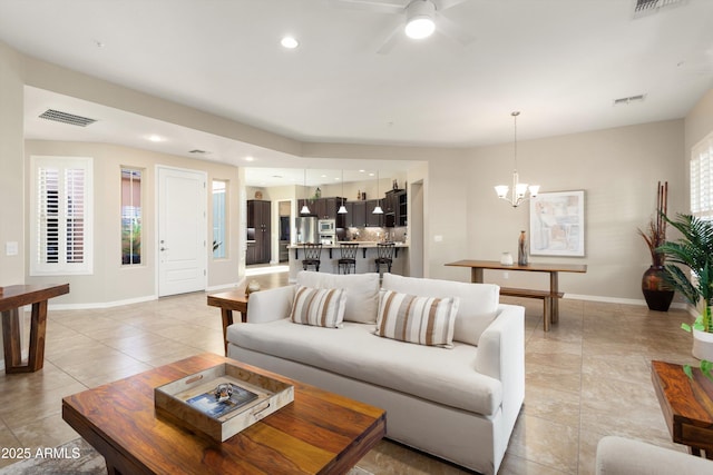 12935 W Lone Tree Trl, Peoria, AZ 85383 - living area with light tile patterned floors, a wealth of natural light, visible vents, baseboards, and ceiling fan with notable chandelier