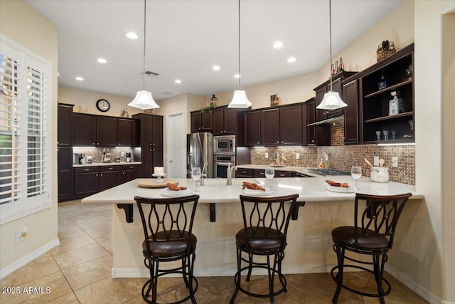 kitchen featuring kitchen peninsula, hanging light fixtures, appliances with stainless steel finishes, and a breakfast bar area