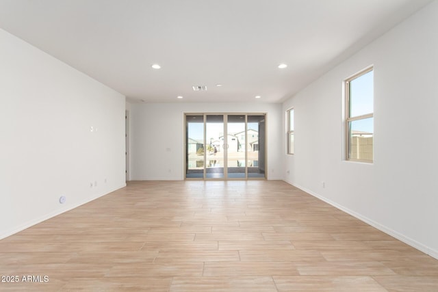 empty room with light hardwood / wood-style floors and plenty of natural light