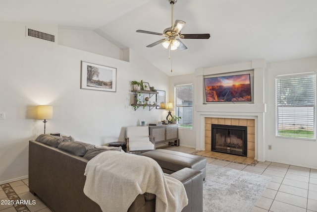 tiled living room featuring vaulted ceiling, ceiling fan, and a fireplace