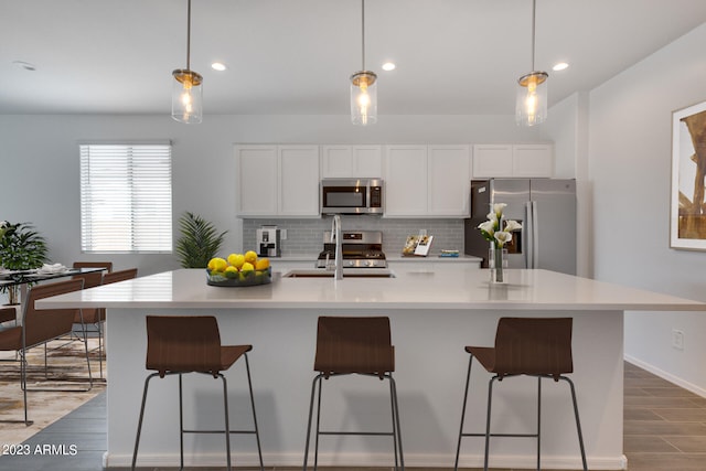 kitchen featuring appliances with stainless steel finishes, hanging light fixtures, and tasteful backsplash