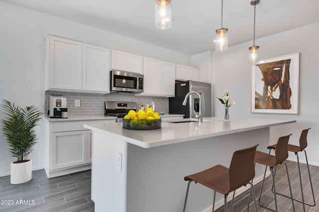 kitchen featuring backsplash, hanging light fixtures, appliances with stainless steel finishes, and white cabinetry