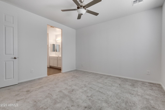 unfurnished bedroom with ceiling fan, light colored carpet, and ensuite bathroom