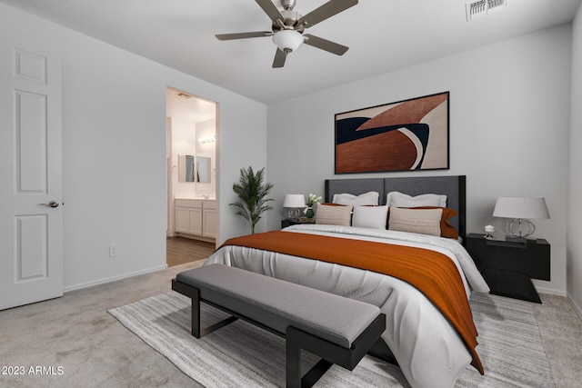 bedroom with ceiling fan, connected bathroom, and light colored carpet