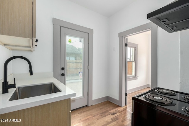 kitchen featuring black range with electric stovetop, sink, light wood-type flooring, light brown cabinetry, and extractor fan