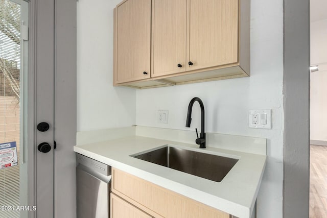 kitchen featuring light brown cabinets, light hardwood / wood-style flooring, stainless steel dishwasher, and sink