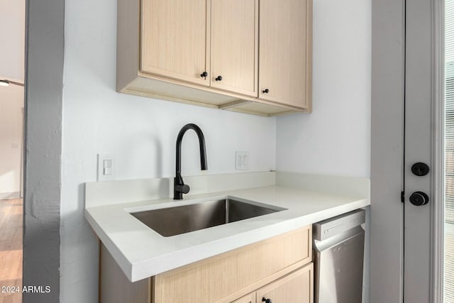 kitchen with dishwasher, light brown cabinets, wood-type flooring, and sink