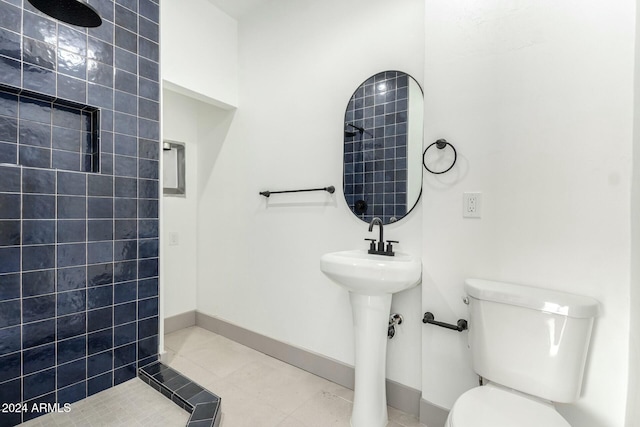 bathroom featuring tiled shower, tile patterned flooring, and toilet