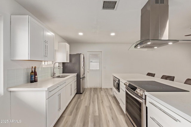 kitchen featuring white cabinetry, stainless steel appliances, a kitchen breakfast bar, and island exhaust hood