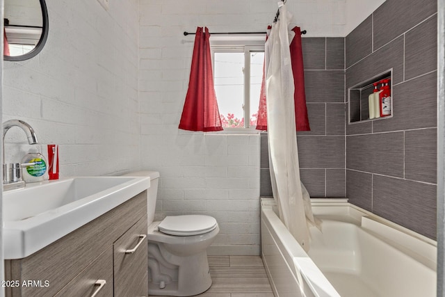 full bathroom with vanity, toilet, shower / tub combo, and tile walls