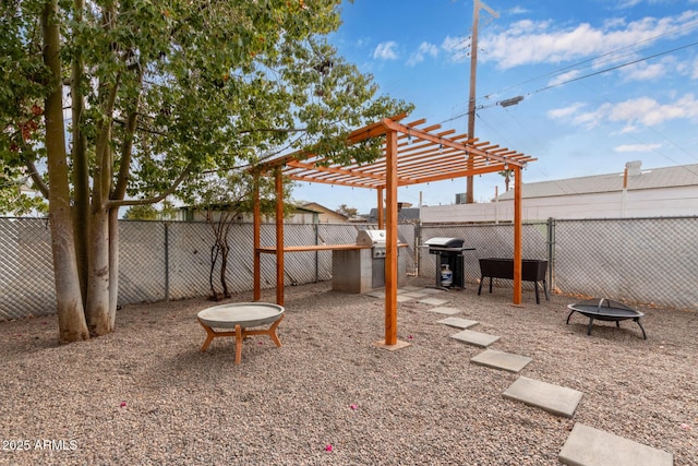 view of patio with area for grilling, a pergola, and a fire pit