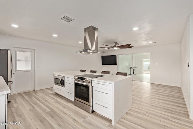 kitchen featuring white cabinetry, island exhaust hood, appliances with stainless steel finishes, and light hardwood / wood-style flooring