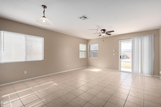 empty room featuring baseboards, visible vents, a ceiling fan, and light tile patterned flooring