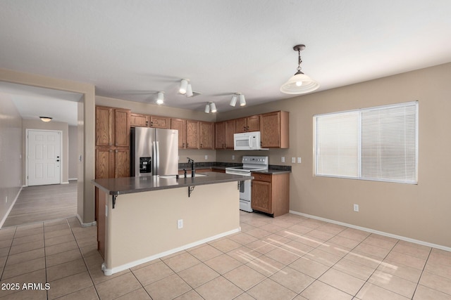 kitchen featuring brown cabinets, light tile patterned floors, dark countertops, a sink, and white appliances