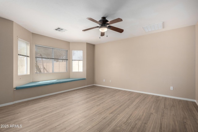 empty room with baseboards, visible vents, and wood finished floors