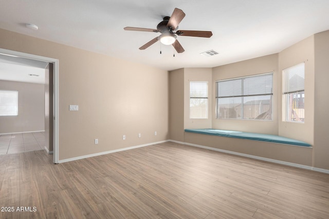 empty room with a wealth of natural light, visible vents, and wood finished floors