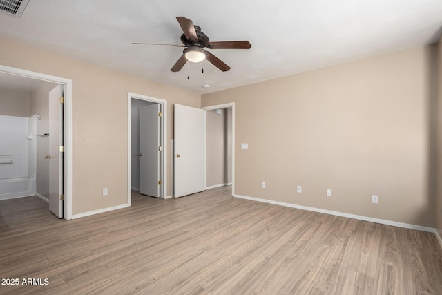 unfurnished bedroom with a spacious closet, light wood-style flooring, visible vents, and baseboards