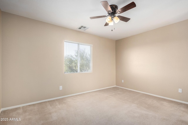 spare room featuring light carpet, a ceiling fan, visible vents, and baseboards