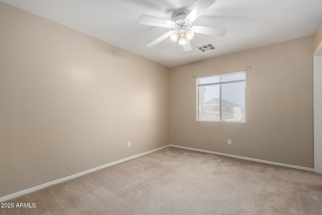 spare room with ceiling fan, visible vents, baseboards, and light colored carpet