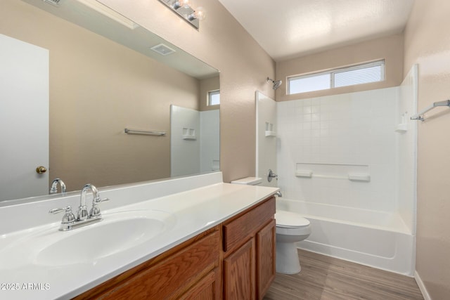 bathroom featuring toilet, wood finished floors, vanity, visible vents, and shower / washtub combination