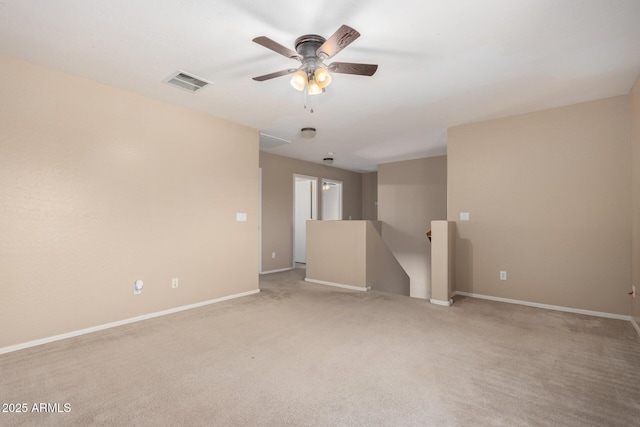 carpeted spare room featuring ceiling fan, visible vents, and baseboards