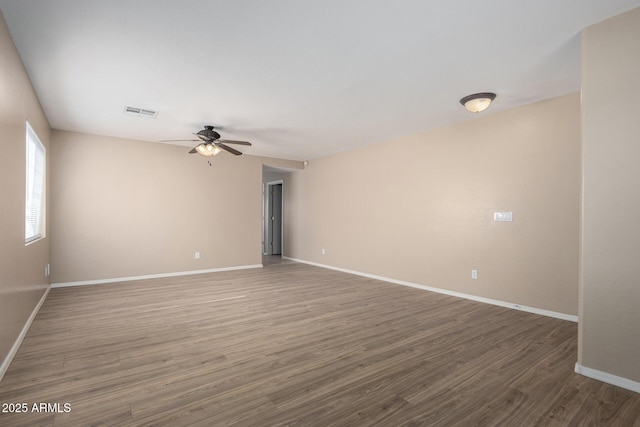 unfurnished room featuring baseboards, visible vents, ceiling fan, and wood finished floors