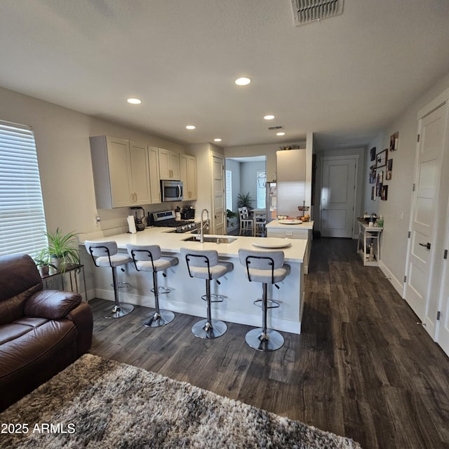 552 Allerton Way, Chino Valley, AZ 86323 - kitchen with stainless steel appliances, dark wood-style flooring, a peninsula, a kitchen breakfast bar, and recessed lighting