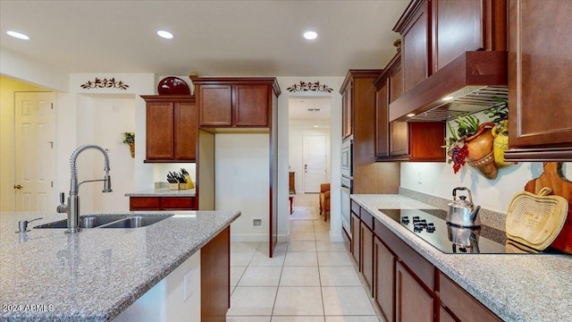 kitchen featuring light stone countertops, wall chimney exhaust hood, black electric cooktop, sink, and light tile patterned flooring