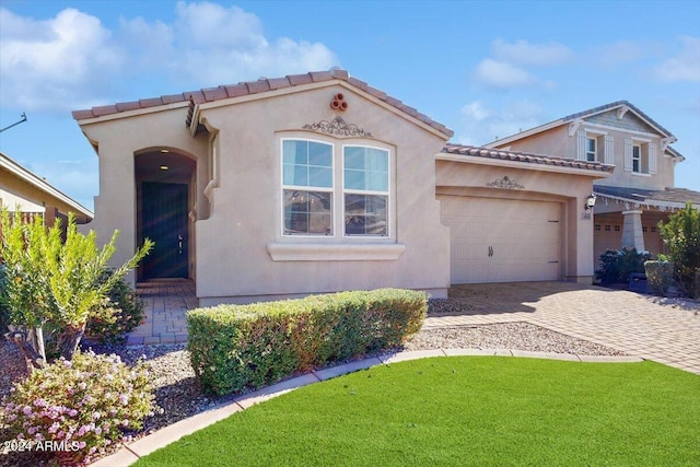 mediterranean / spanish-style home featuring a front yard and a garage