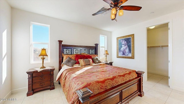 tiled bedroom with ceiling fan, a spacious closet, and a closet