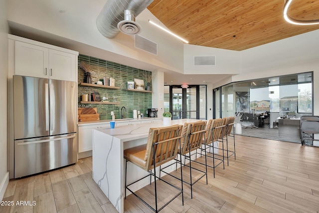 kitchen with wood ceiling, wood tiled floor, visible vents, and freestanding refrigerator