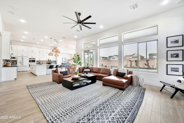 living room with recessed lighting, visible vents, and light wood finished floors