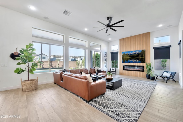 living room featuring light wood finished floors, visible vents, a large fireplace, and recessed lighting