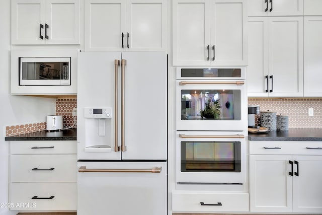 kitchen with white appliances, dark countertops, white cabinets, and decorative backsplash