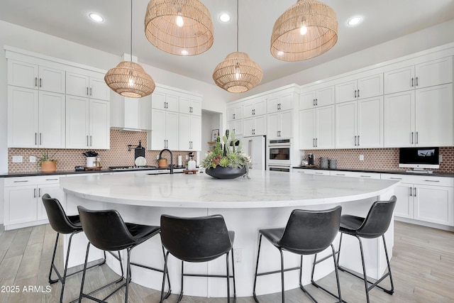 kitchen with light wood-type flooring, white appliances, white cabinets, and decorative backsplash