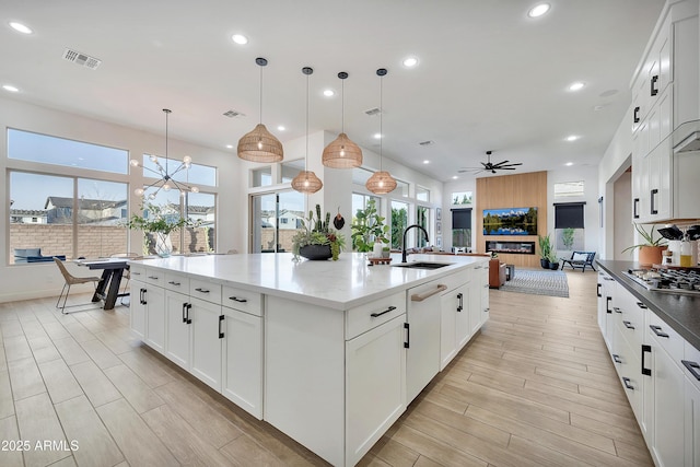 kitchen featuring visible vents, stainless steel gas stovetop, wood tiled floor, open floor plan, and a sink