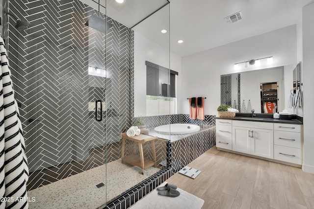 full bathroom featuring a stall shower, visible vents, wood finished floors, vanity, and a bath