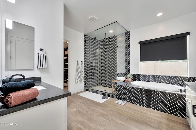 bathroom with a garden tub, visible vents, a stall shower, vanity, and wood finished floors