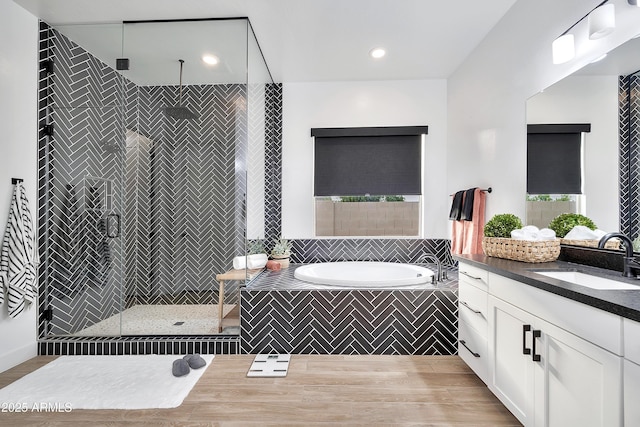 full bathroom with wood finished floors, a stall shower, a garden tub, and vanity