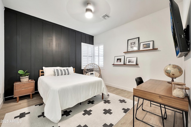 bedroom with ceiling fan, light wood finished floors, visible vents, and baseboards